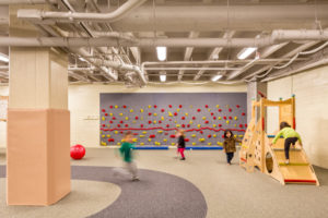 Children playing at indoor playground with a rock wall and SafeLandings Shock Absorbing Flooring.