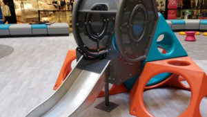 Children's slide at an indoor mall play area with SafeLandings wood grain sheet vinyl system.