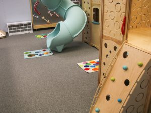 Carpet that meets safety standards for indoor play grounds and a wooden play fixture.