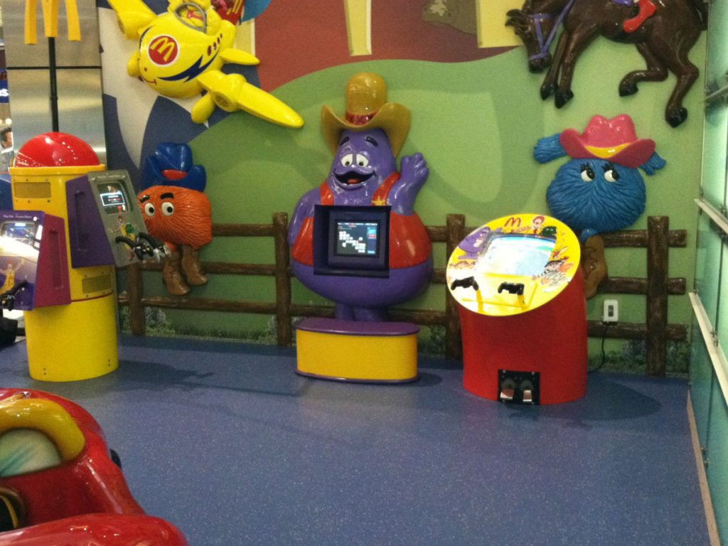 McDonald's Play Area with impact absorbing sheet vinyl flooring. The flooring is purple and there are several video games to play.