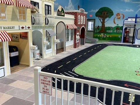 SafeLandings Shock Absorbing Carpet System installation in church play room meeting ASTM F1292 standards. The carpet is a custom print with roads, surround by store play buildings placed on the walls.